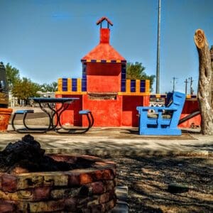 A red building with a blue chair and table in front of it.