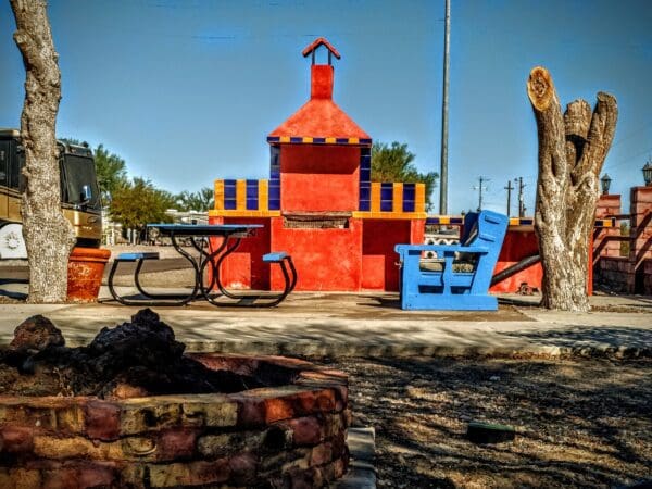 A red building with a blue chair and table in front of it.